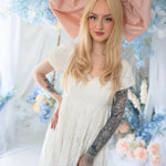 Dauphine Lace Gown styled with oversized pink bow, showcasing romantic lace and empire silhouette in a whimsical wedding setting.