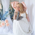 Model in Dauphine Lace Gown crouched in floral wedding scene, highlighting gown's lace detail and soft bridal aesthetic.