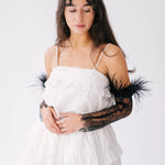 White layered party dress with black feathered lace sleeve gloves.