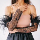 Elegant black lace arm sleeves with feather trim paired with a pink top and tulle skirt.