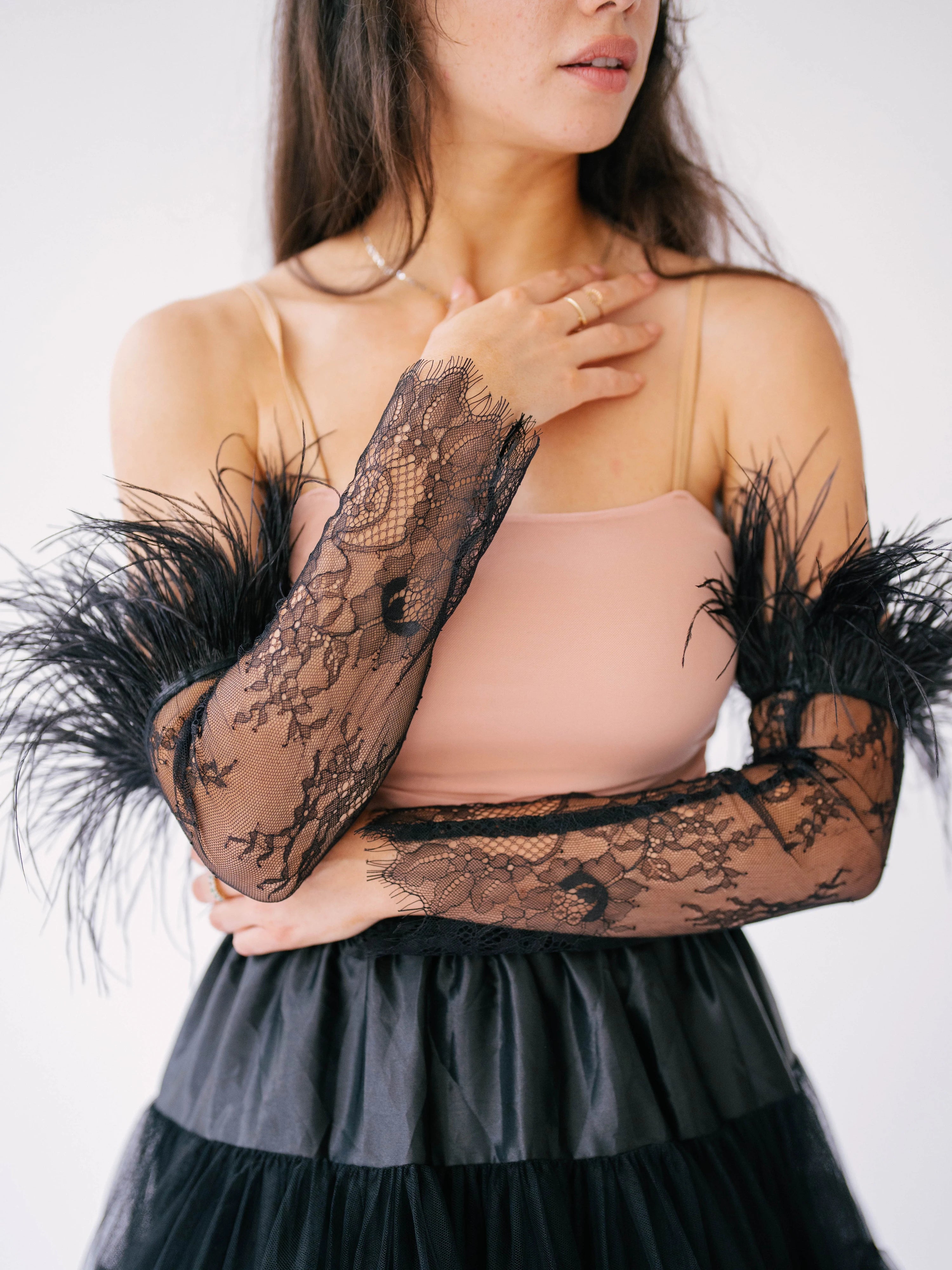 Elegant black lace arm sleeves with feather trim paired with a pink top and tulle skirt.
