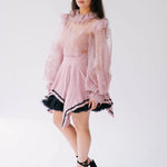Women's pink ruffled lace top with long sheer sleeves.
