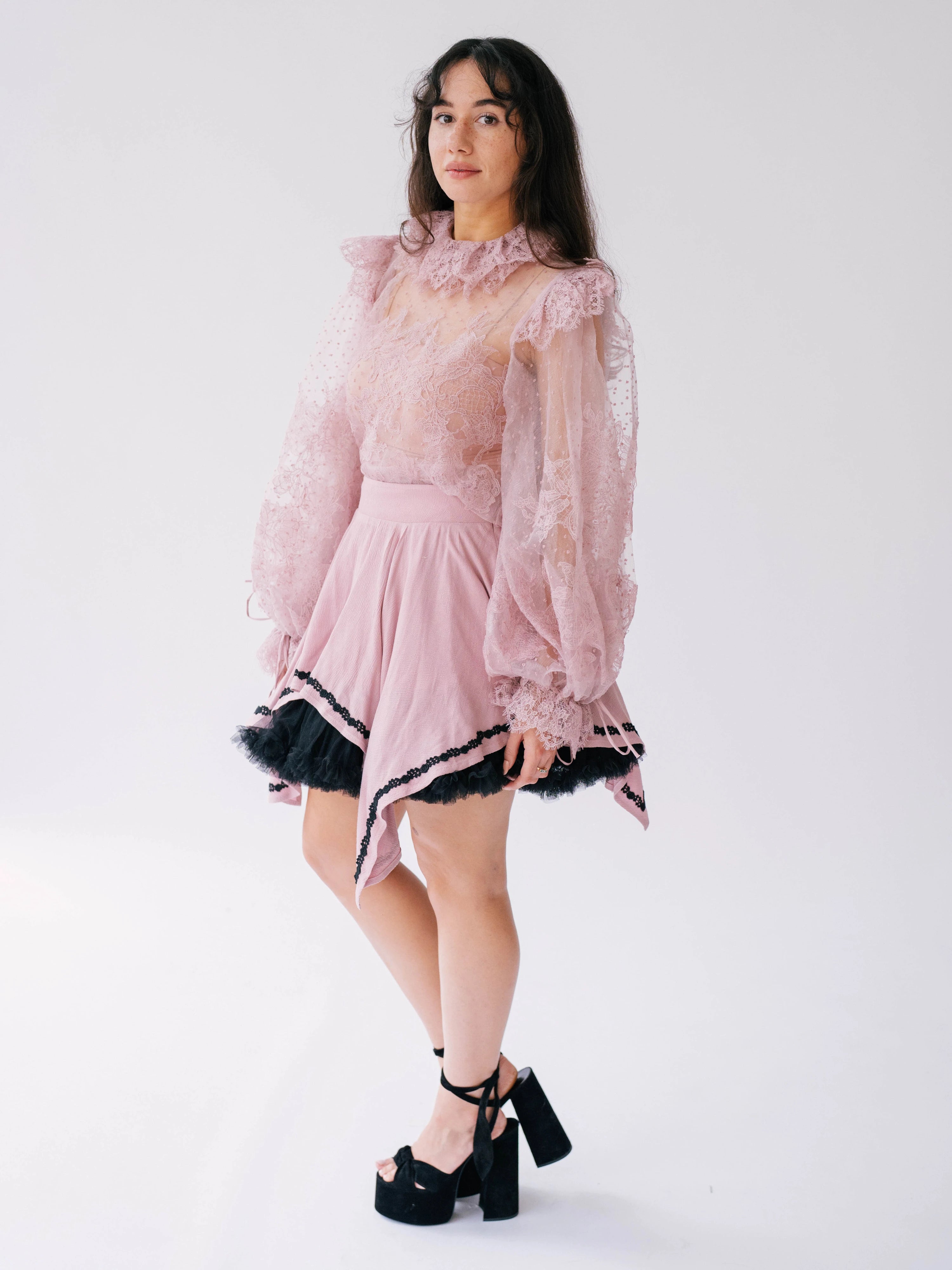 Women's pink ruffled lace top with long sheer sleeves.