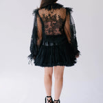 Women's sheer black lace blouse with long puff sleeves shown from the back.