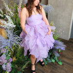 Lavender tulle Eventyr Tulip Dress with ruffled layers, hand cut and hand dyed worn by a woman surrounded by florals.