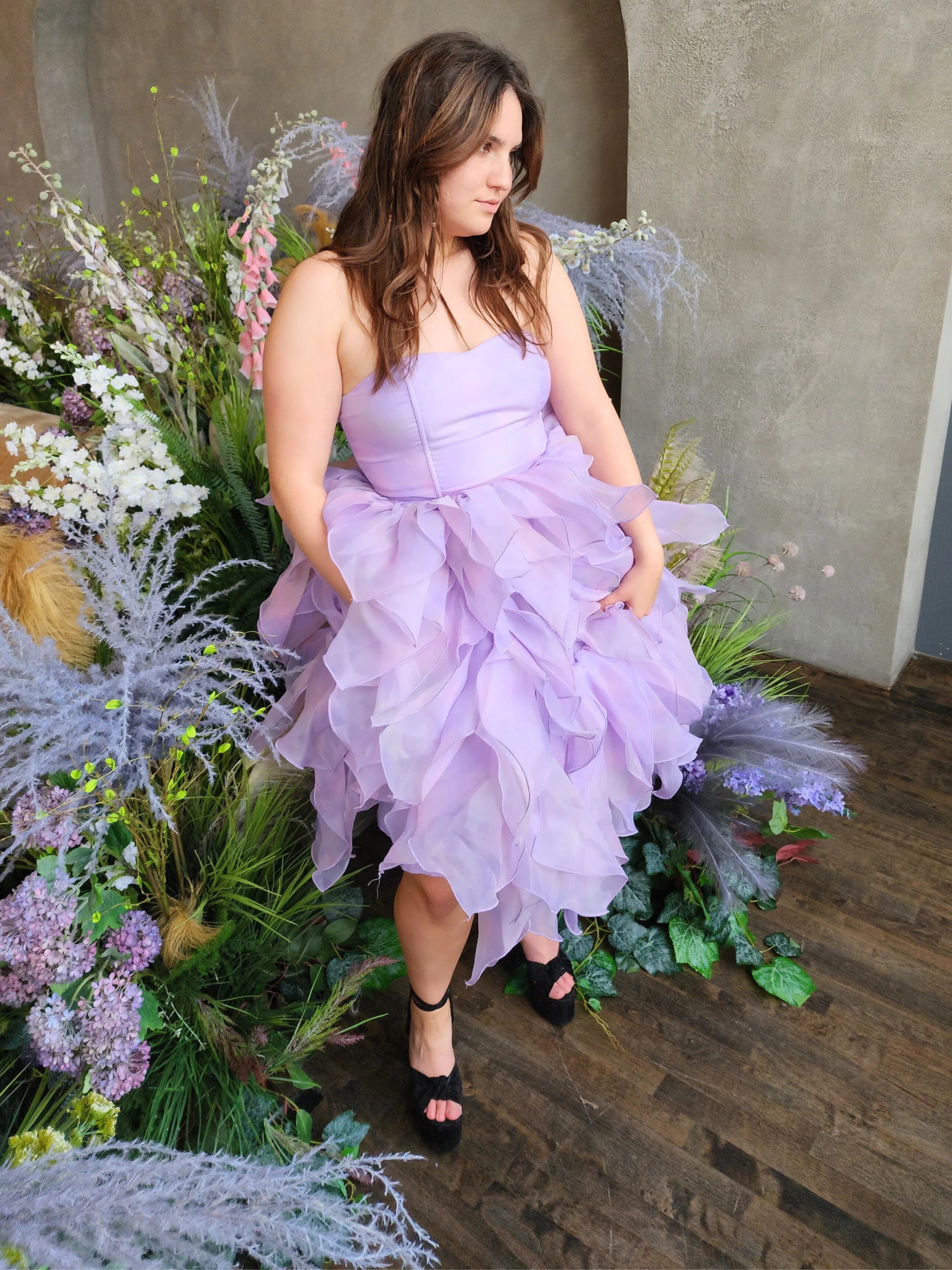 Lavender tulle Eventyr Tulip Dress with ruffled layers, hand cut and hand dyed worn by a woman surrounded by florals.