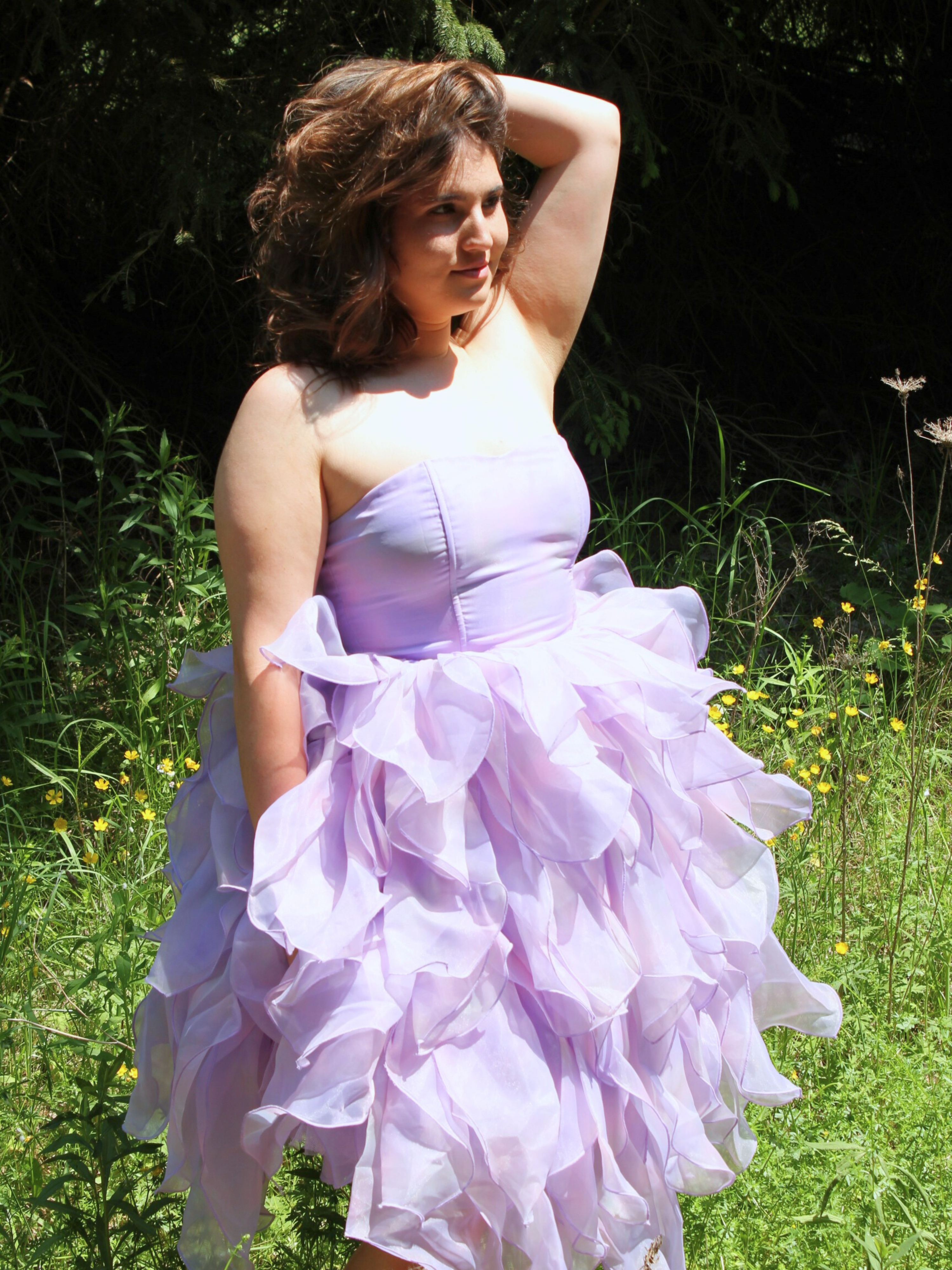 Lavender ruffled Eventyr Tulip Dress with fitted bodice and voluminous hand-dyed skirt worn by a woman in a field to create a fairytale experience.