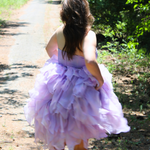 Lavender tulle Eventyr Tulip Dress with ruffled layers worn by a woman on a path.