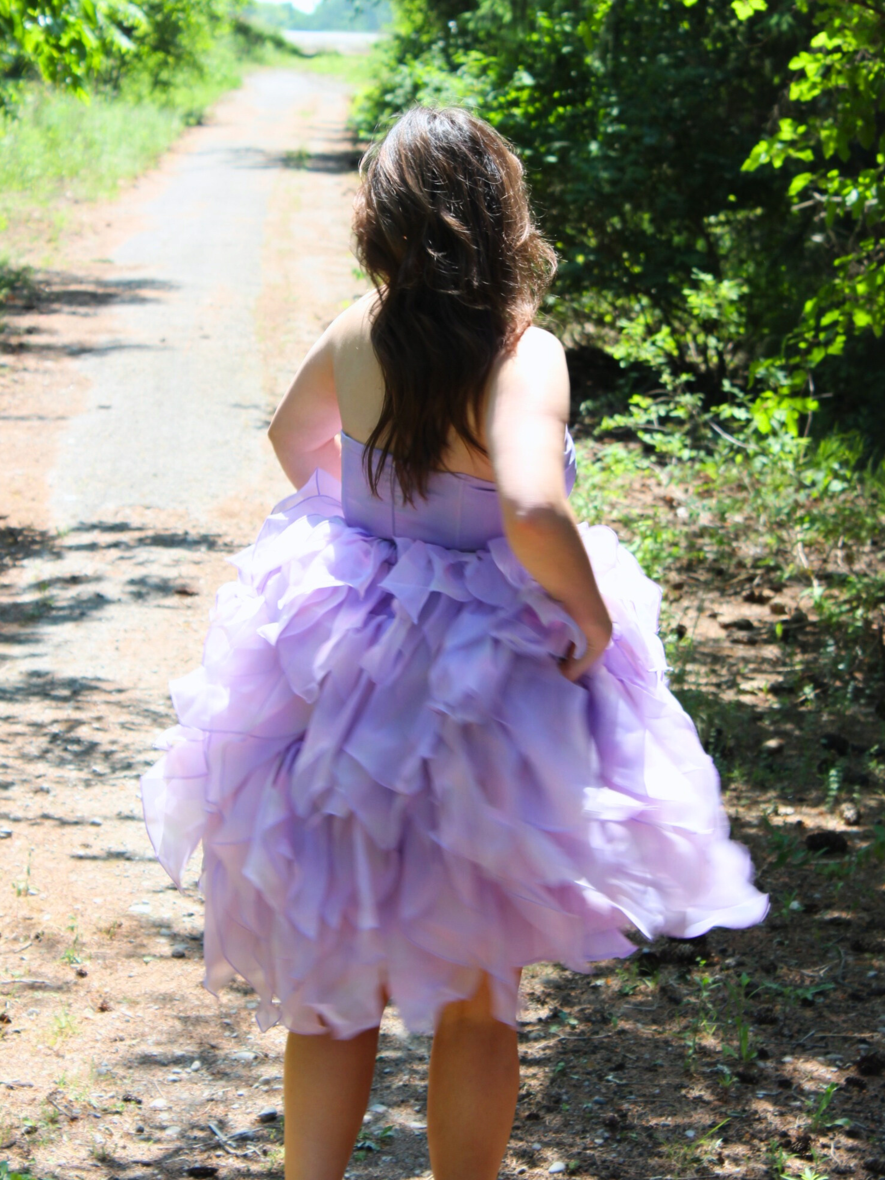 Lavender tulle Eventyr Tulip Dress with ruffled layers worn by a woman on a path.