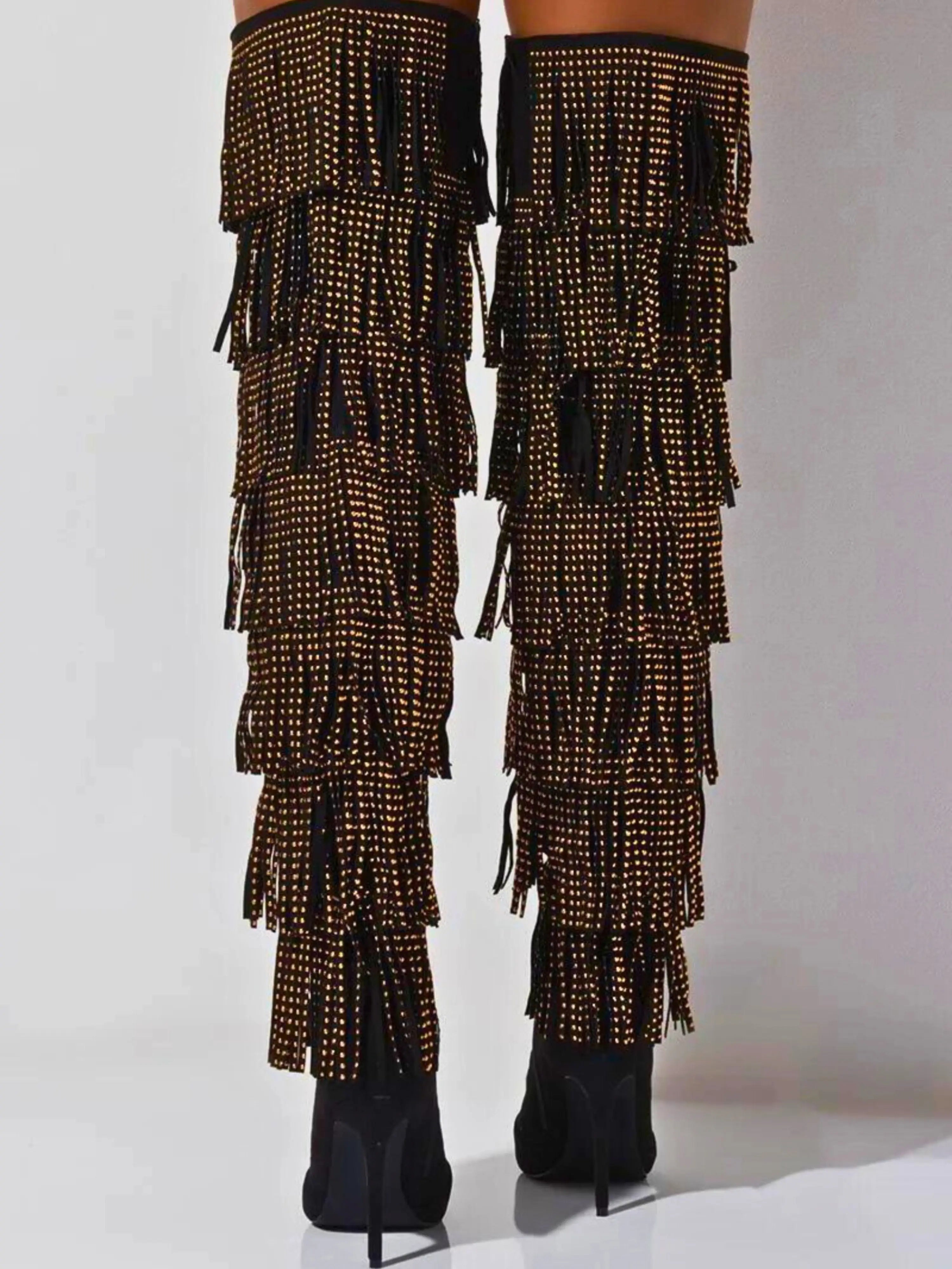 Black suede thigh high boots with tiered gold studded fringe running down the back.