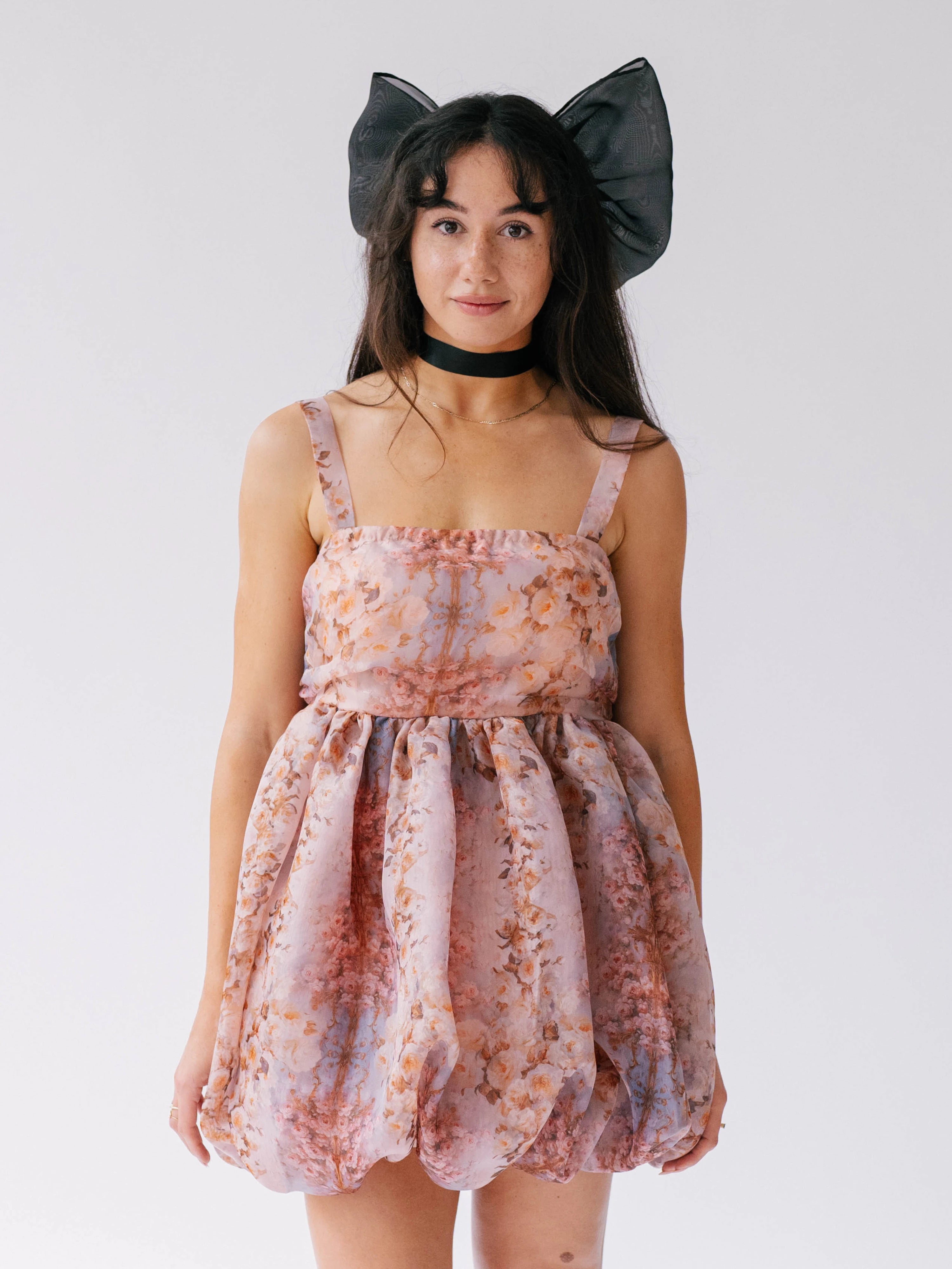 Pink floral bubble mini dress with black bow headpiece and choker, perfect for a whimsical fashion look.