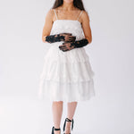 White tiered sundress with spaghetti straps paired with black lace opera gloves and platform sandals.