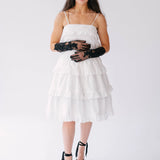White tiered sundress with spaghetti straps paired with black lace opera gloves and platform sandals.
