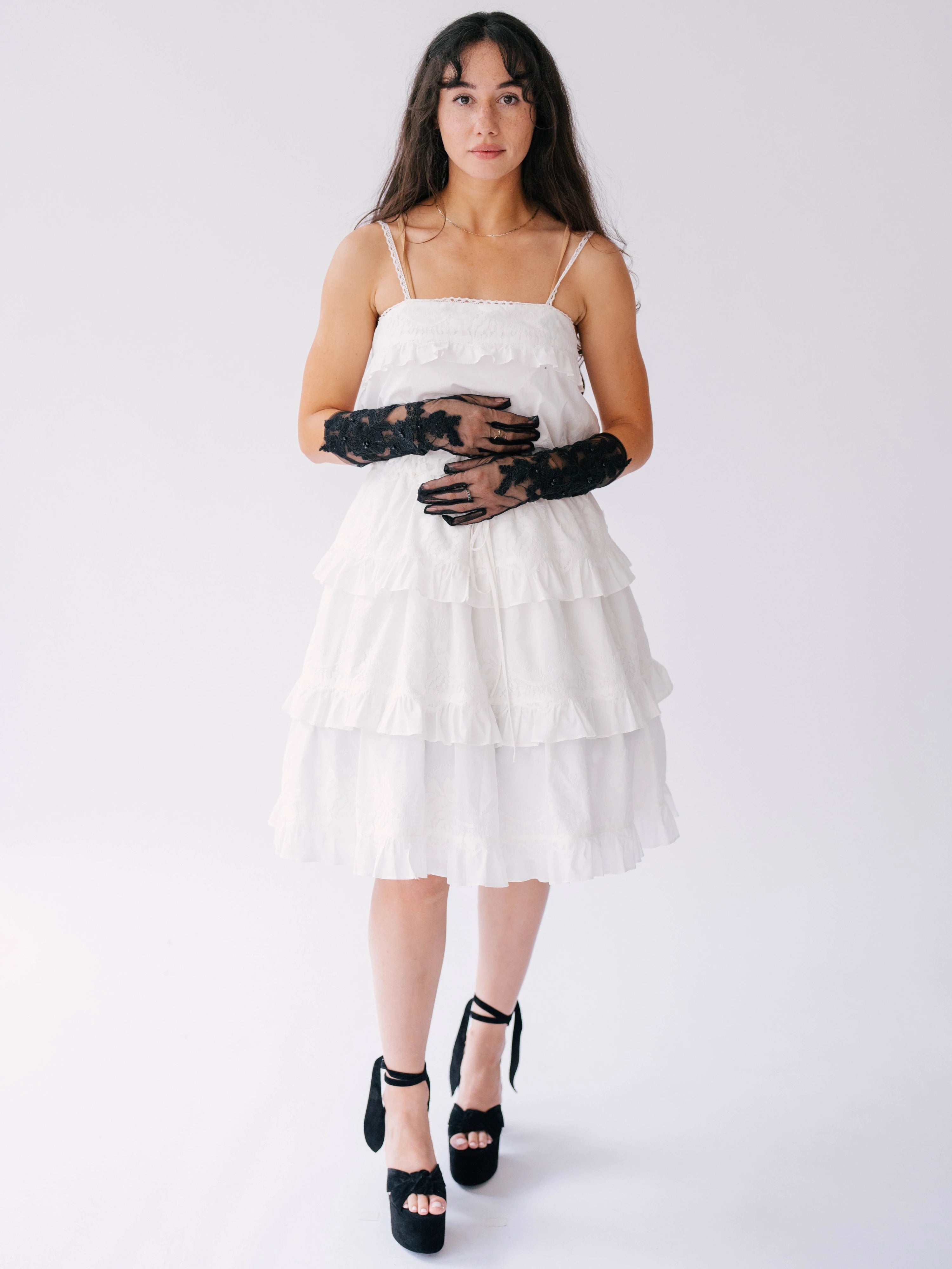 White tiered sundress with spaghetti straps paired with black lace opera gloves and platform sandals.