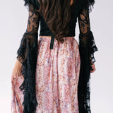 Long-sleeved black lace corset top paired with a pink floral maxi skirt that bustles.