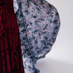 Red velvet midi dress showcasing the contrasting floral print from the cloak worn overtop.