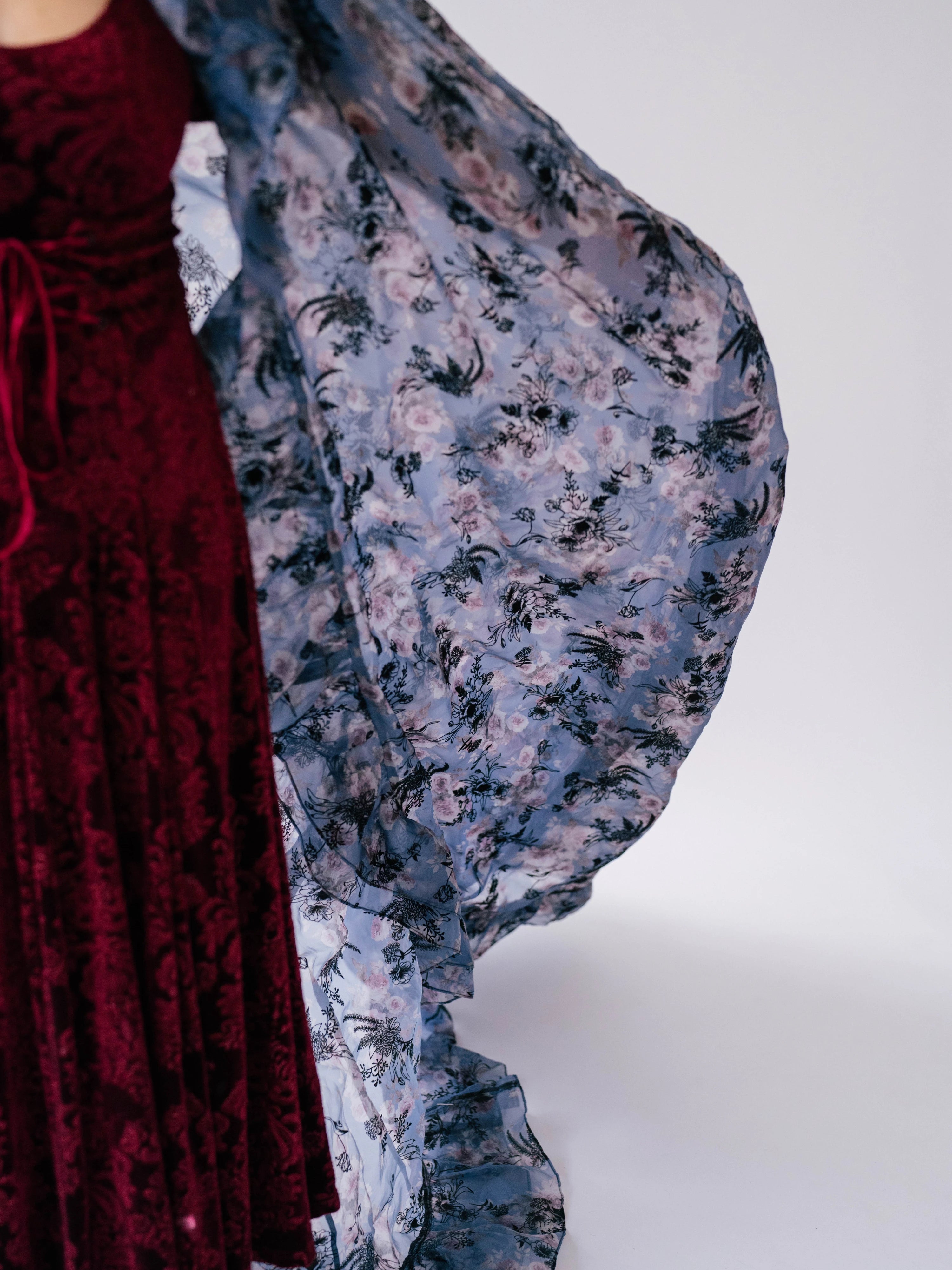 Red velvet midi dress showcasing the contrasting floral print from the cloak worn overtop.