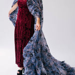 Burgundy velvet dress paired with a flowing floor length cape designed with a blue and purple floral print.