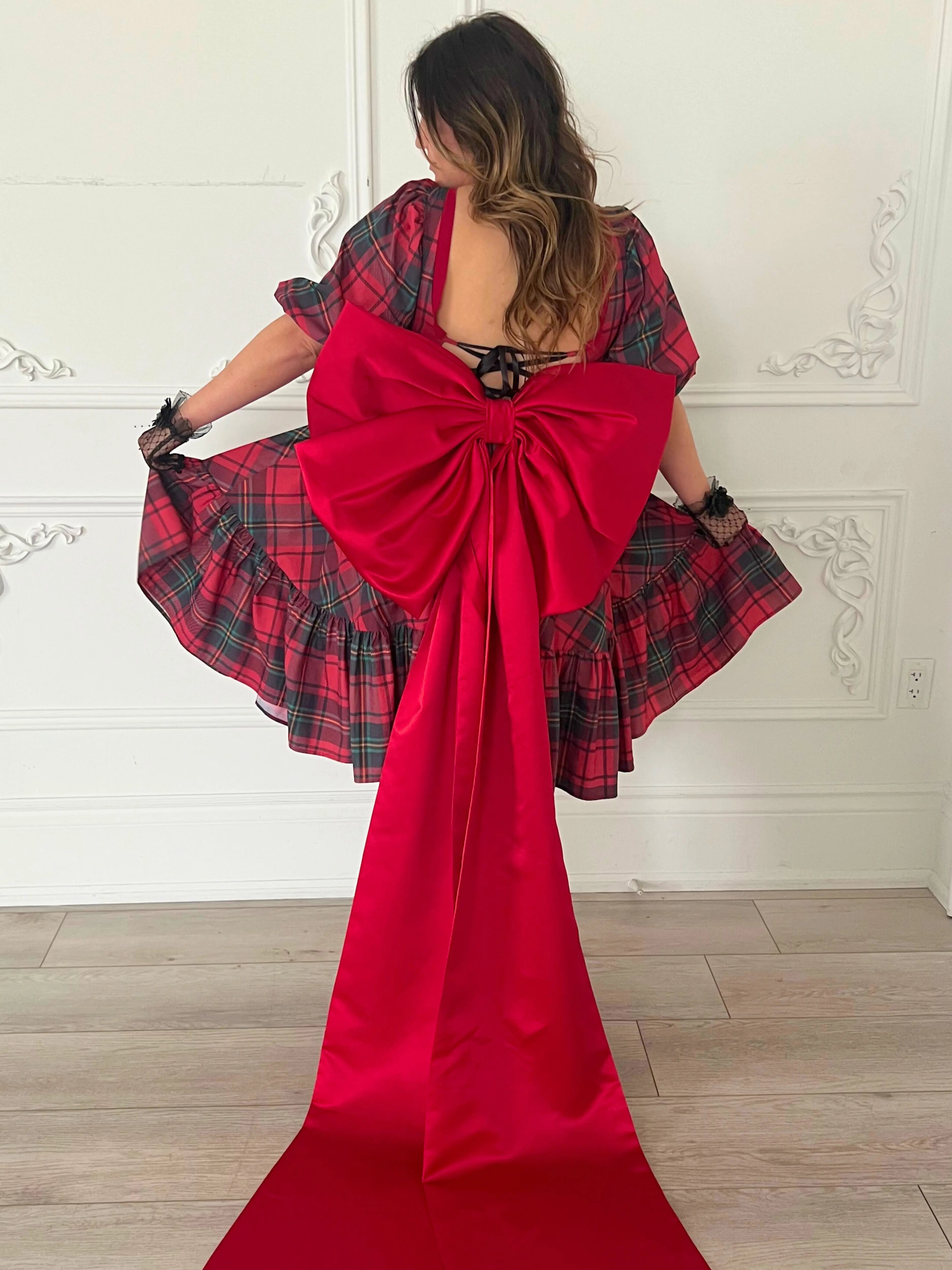 The Josephine Plaid Dress with a dramatic oversized red bow belt trailing to the floor.