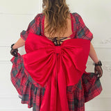 A plaid corset midi dress with a dramatic red bow belt tied at the back.