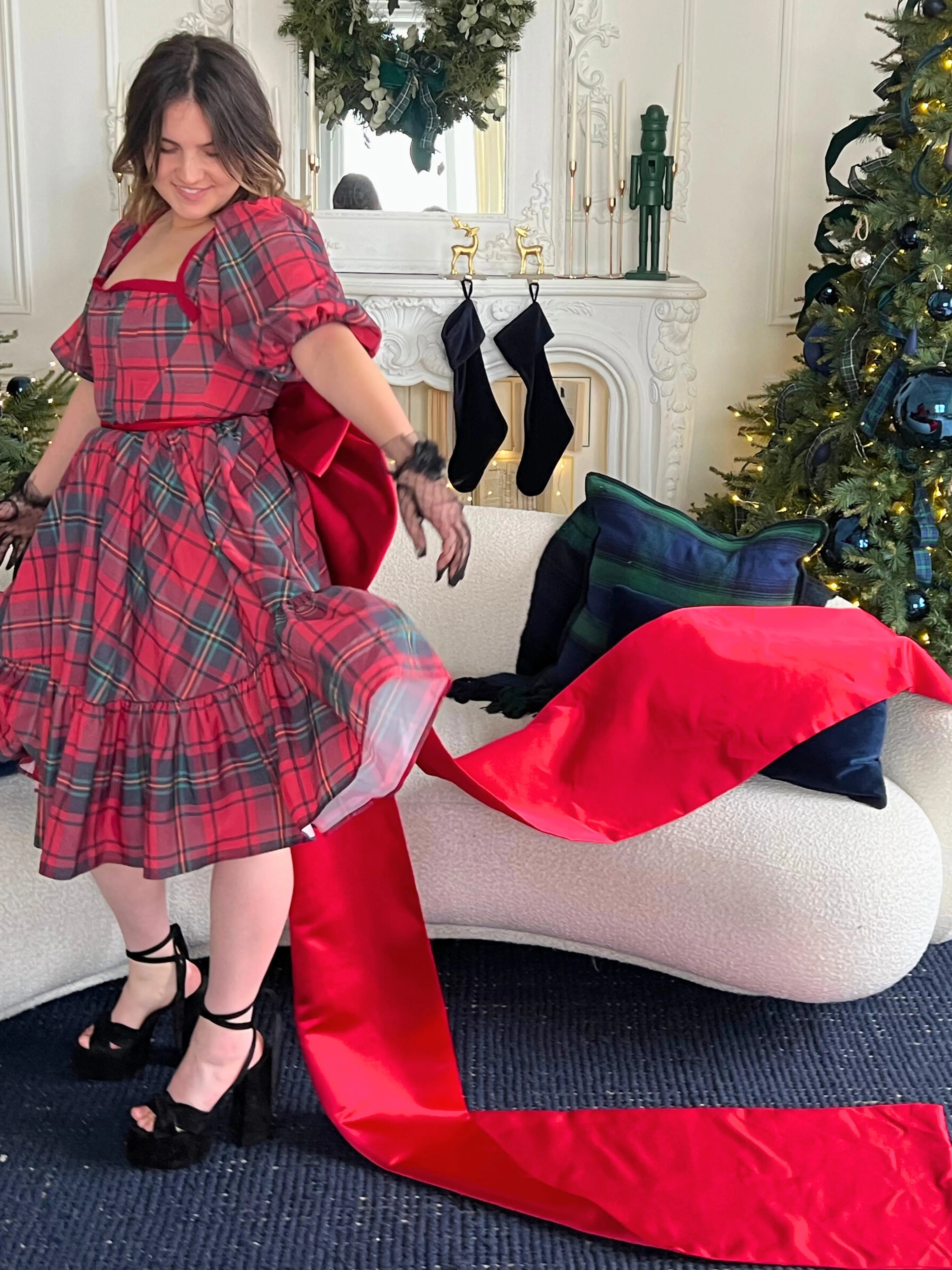 Red and green plaid dress with ruffled tiers and short sleeves styled with The Holiday Red Bow Belt, an oversized waist bow accessory.