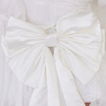 White large satin bow with crisp, structured folds.