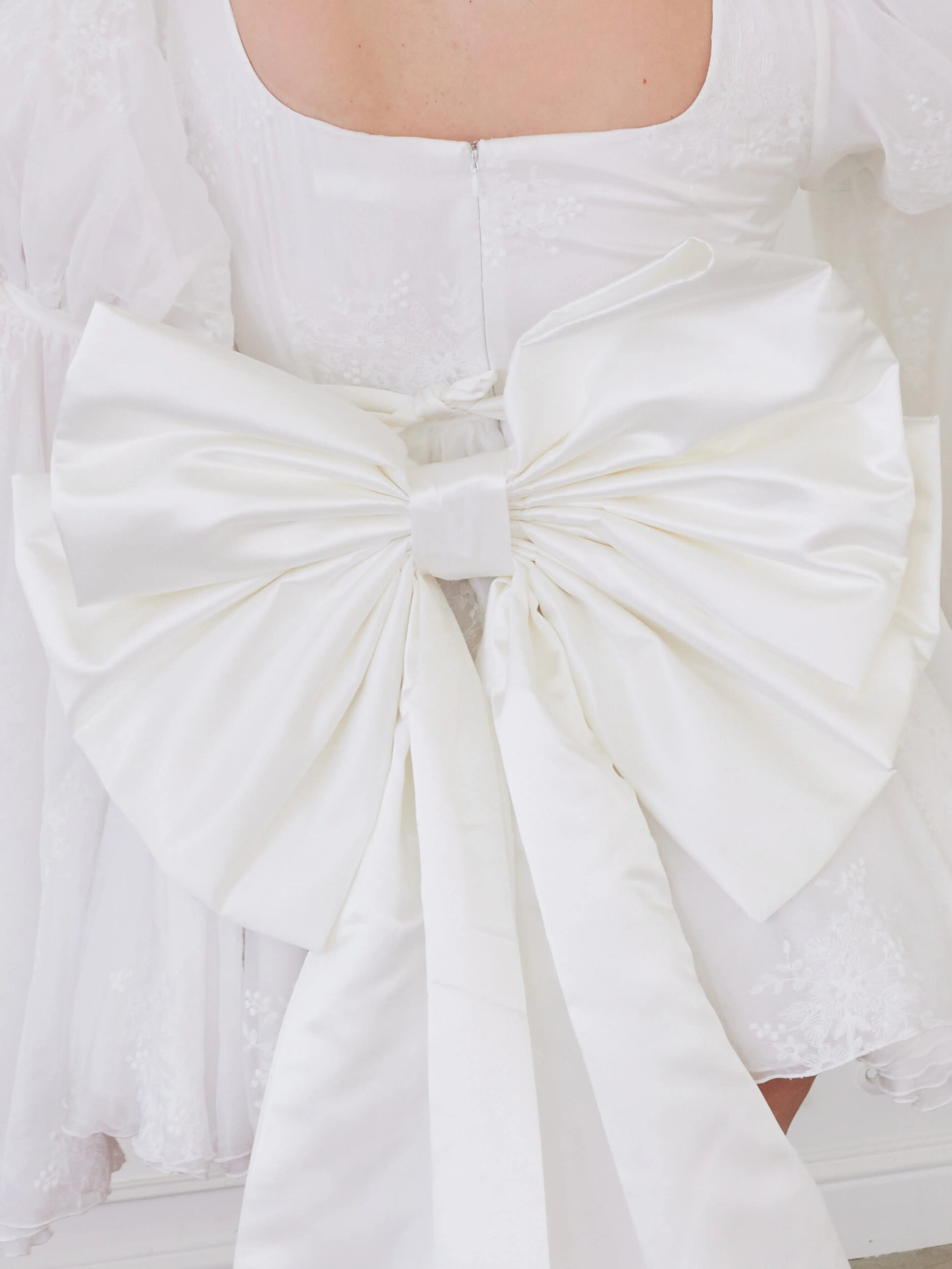 White large satin bow with crisp, structured folds.