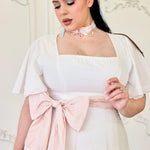 White swiss dot cotton midi dress with a pink bow sash, square neckline and flutter sleeves.