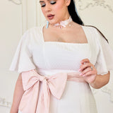 White swiss dot cotton midi dress with a pink bow sash, square neckline and flutter sleeves.