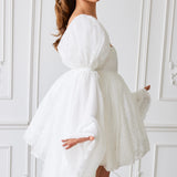 Flowy white mini dress with billowing long sleeves and a tied waist.