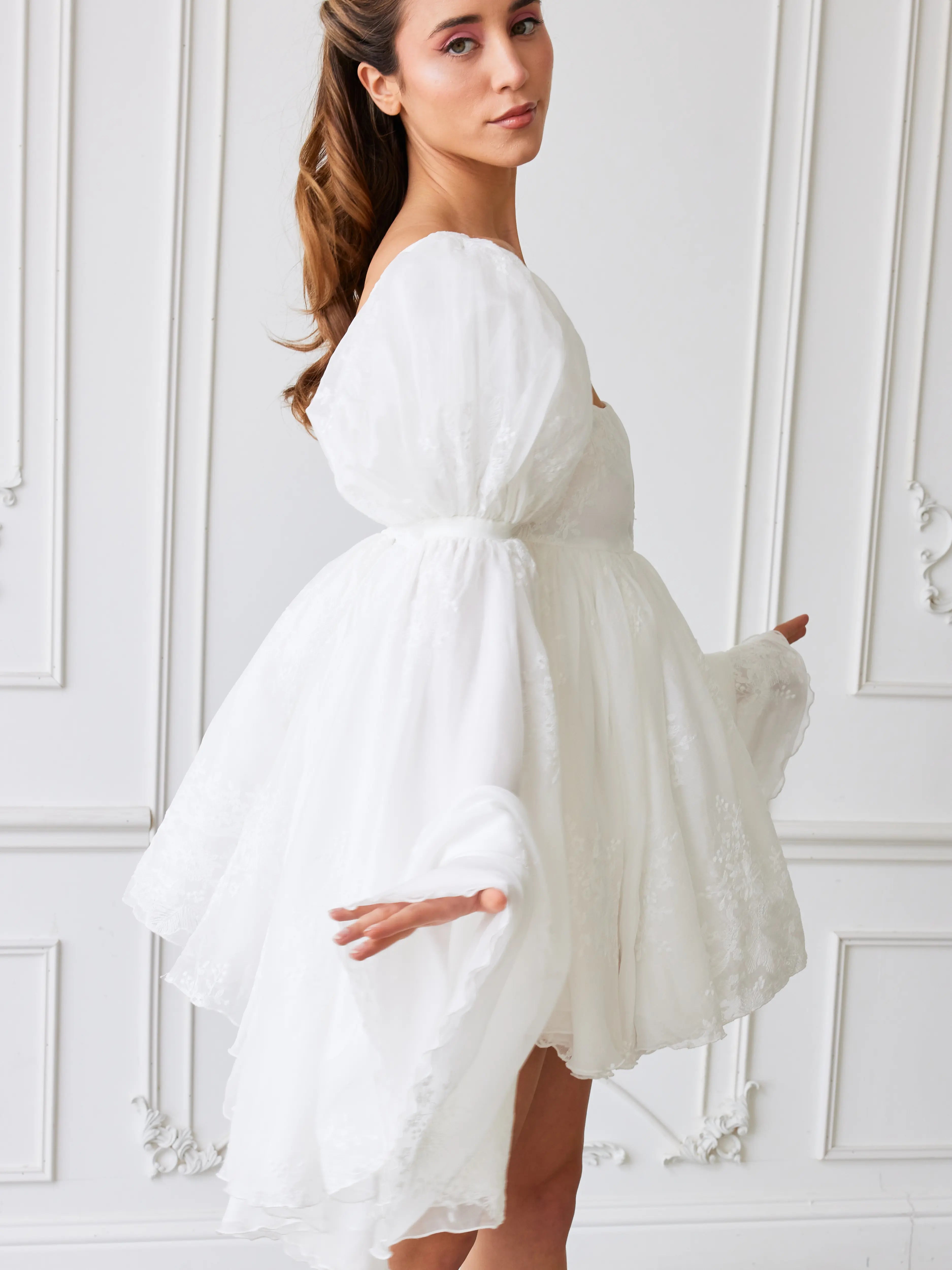 Flowy white mini dress with billowing long sleeves and a tied waist.