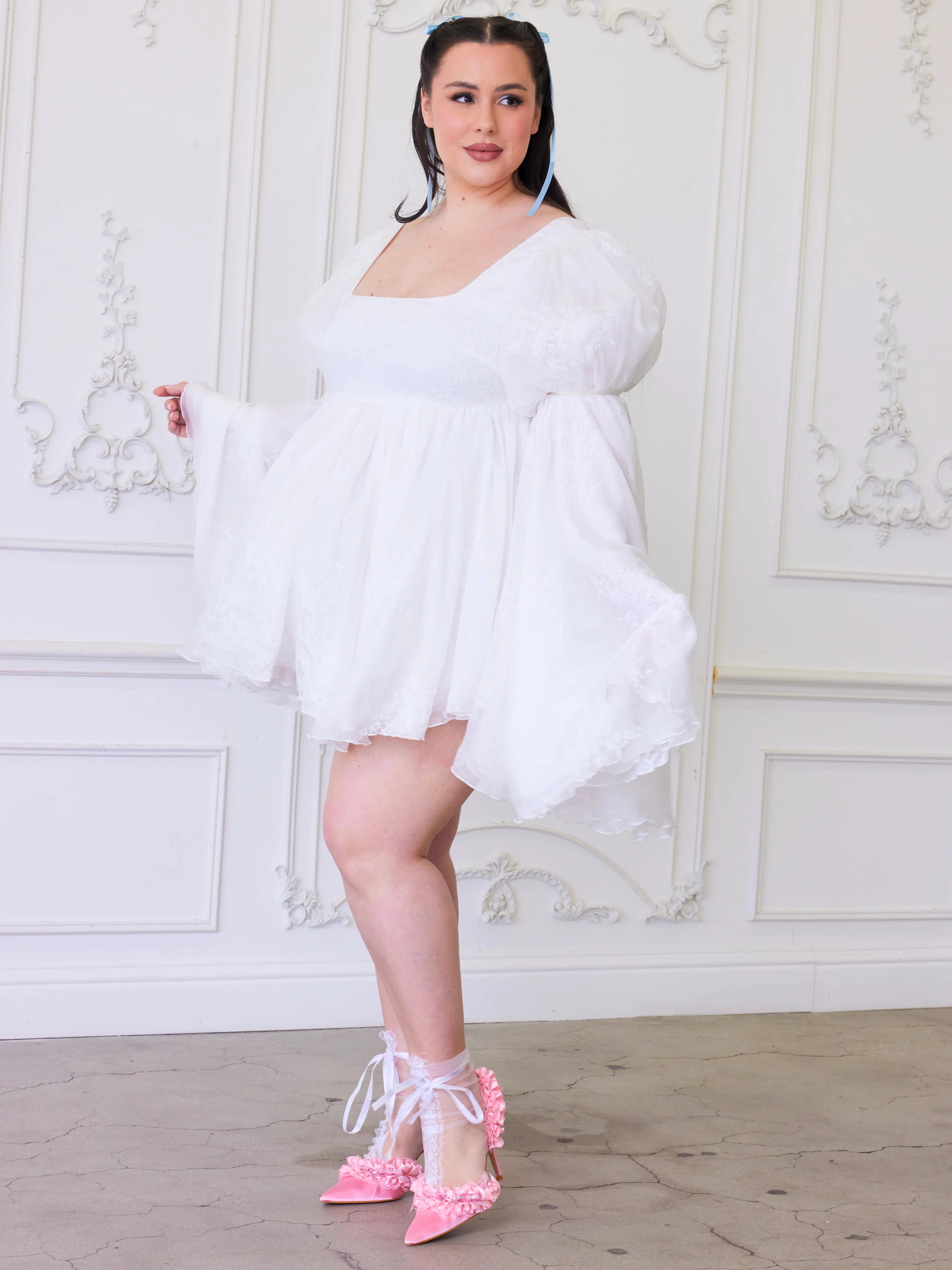 A white mini dress with oversized lace sleeves paired with pink ballet heels.