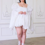 An elegant white mini dress with puffy oversized bell sleeves and pink heels.