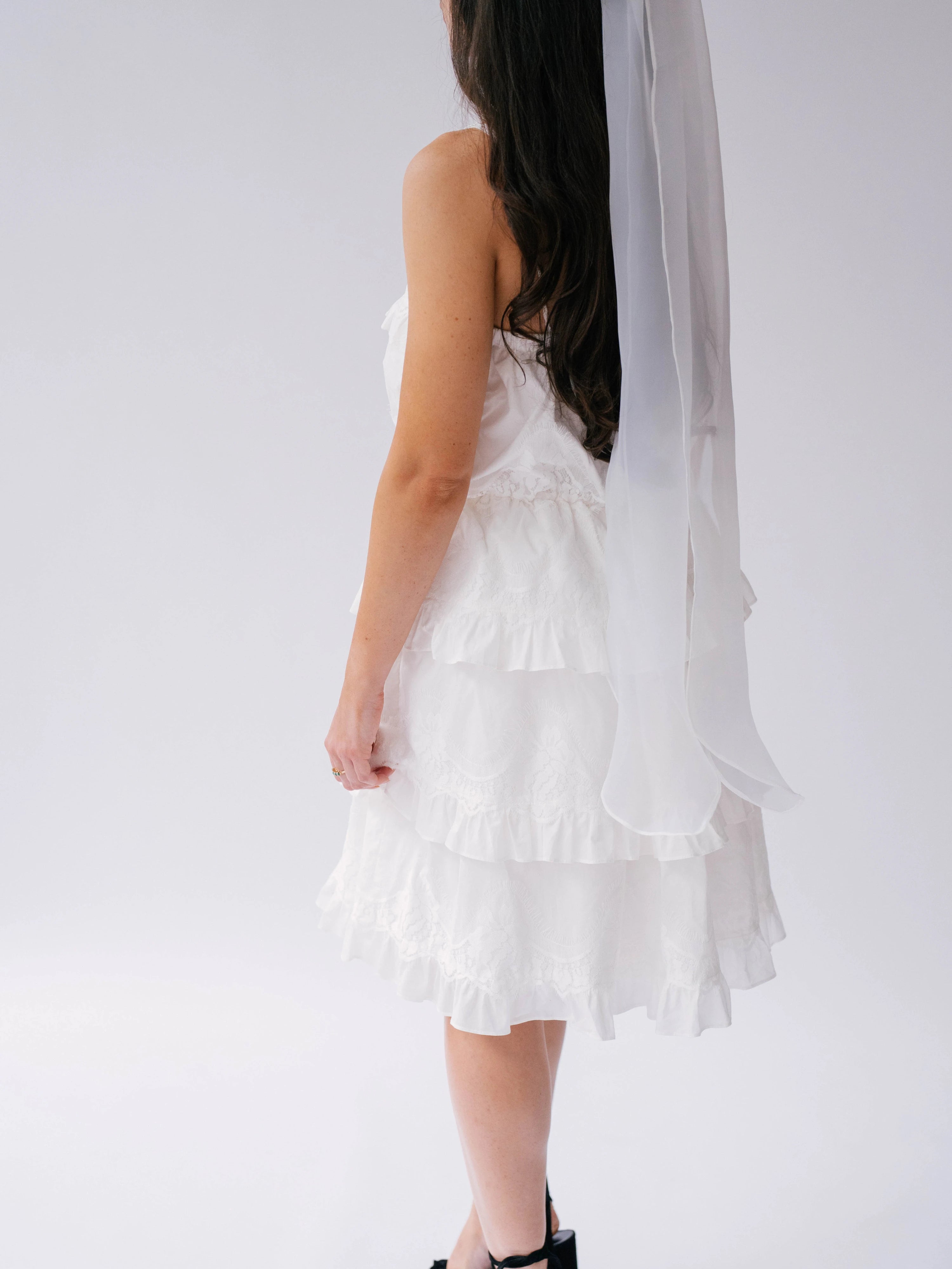 White ruffled dress with tiered layers and The Ivory Grand Bridal Hair Bow viewed from the side.