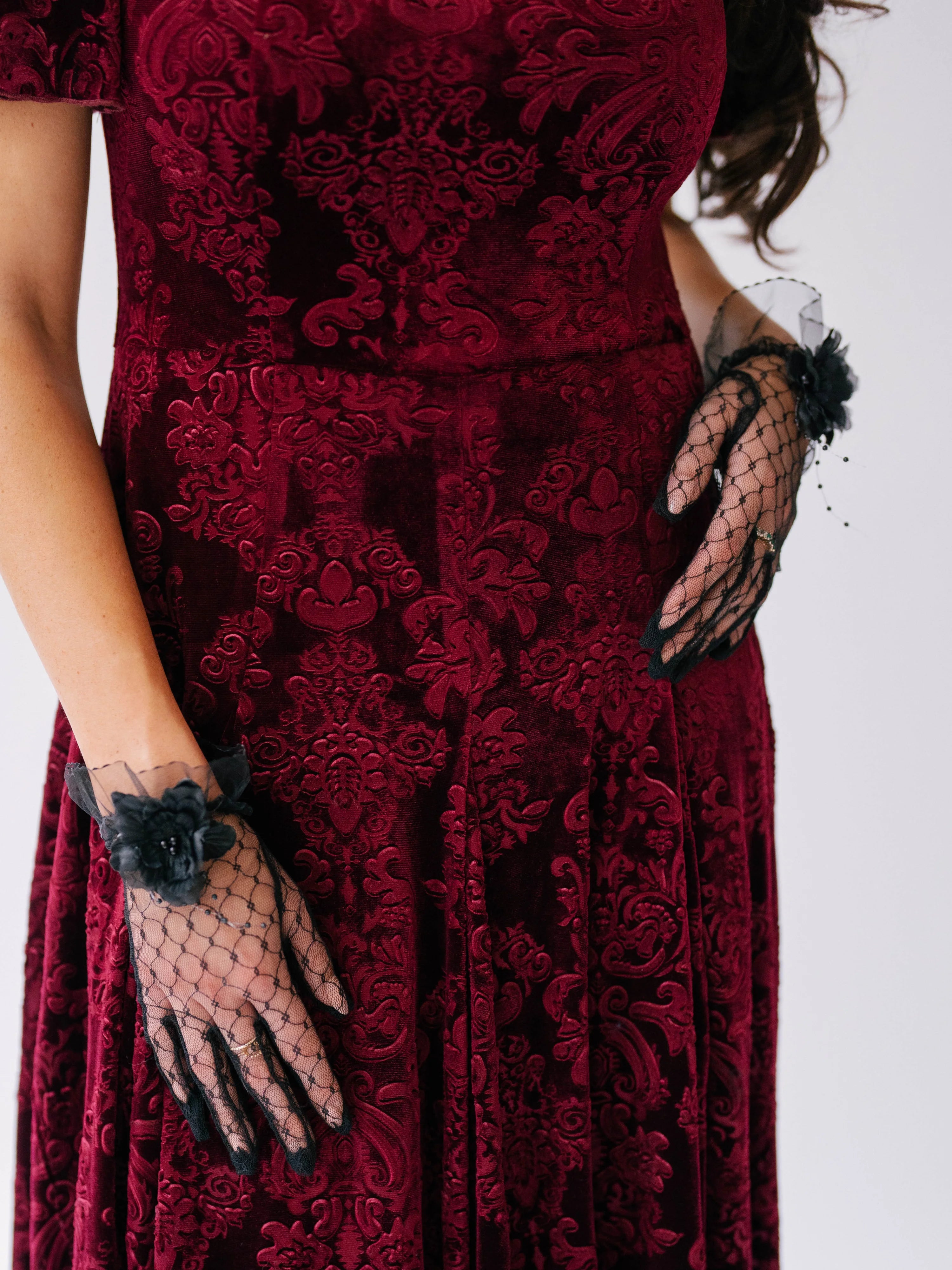 Scarlet red velvet midi dress with ornate damask patterns and black lace evening gloves.