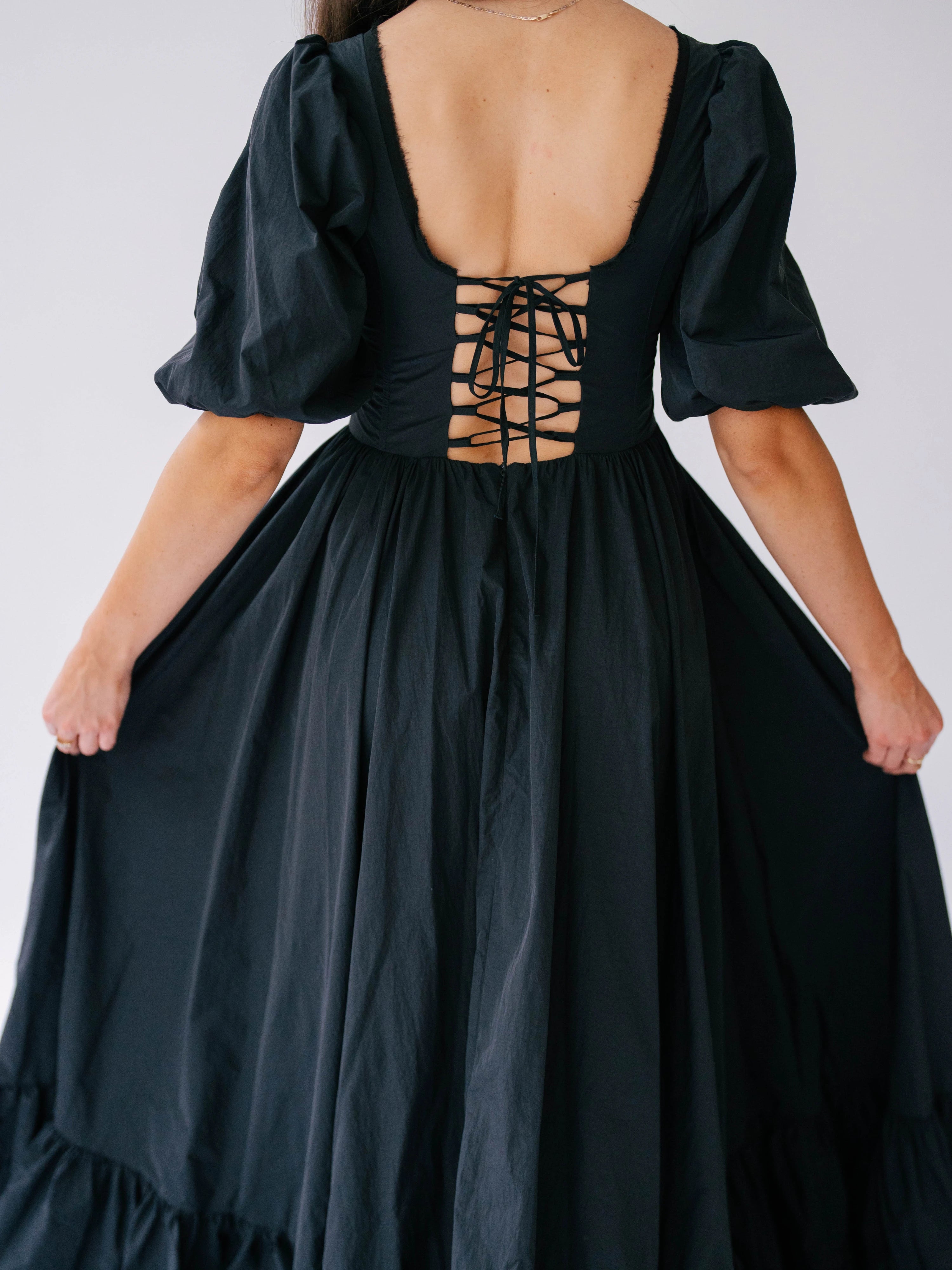 Black corset-style bodice maxi dress with puff sleeves and a lace-up back.