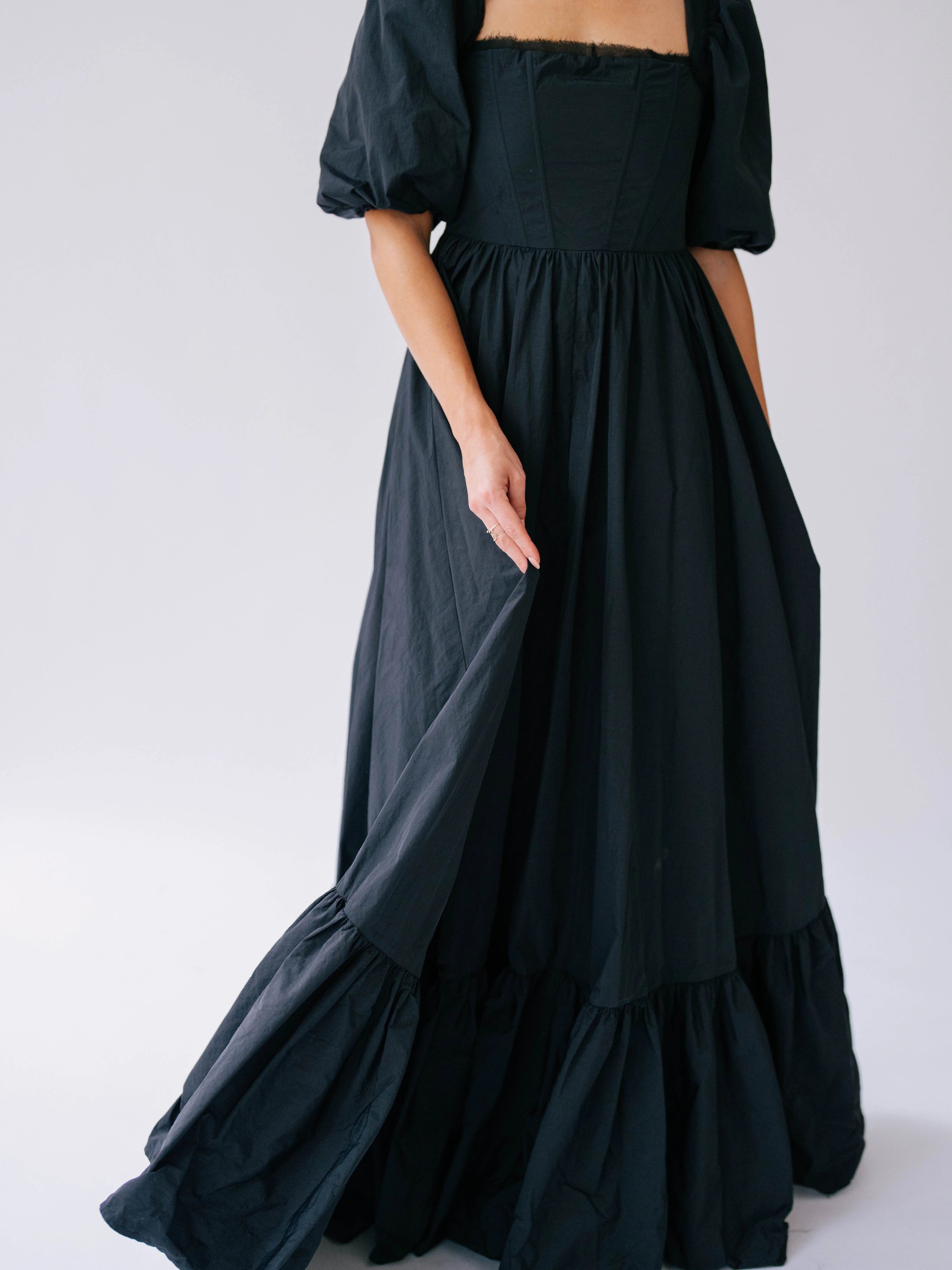 The Josephine Renaissance Gown in Raven is a black taffeta corset maxi dress with puff sleeves and a tiered ruffle hem.