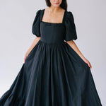 The Josephine Renaissance Gown is a Black taffeta corset dress with puff sleeves and a ruffled hem.