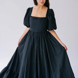 The Josephine Renaissance Gown is a Black taffeta corset dress with puff sleeves and a ruffled hem.