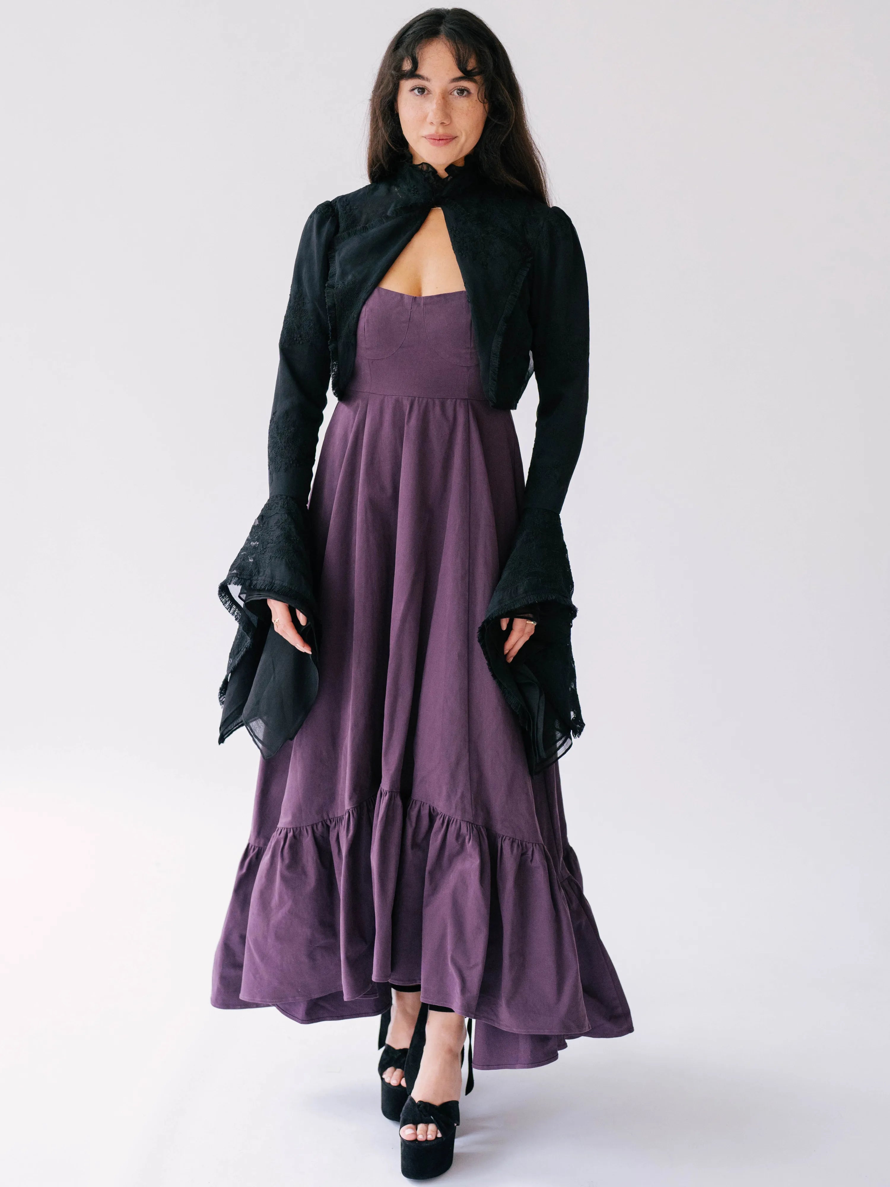 Purple midi dress with ruffled hem paired with a black shrug bell sleeve black lace jacket.