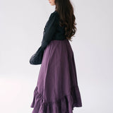 A flowing purple midi dress with ruffled hem detailing underneath The Lady Elizabeth Midnight Black Victorian Jacket.
