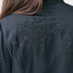 Black jacket with intricate embroidered floral design on the back.