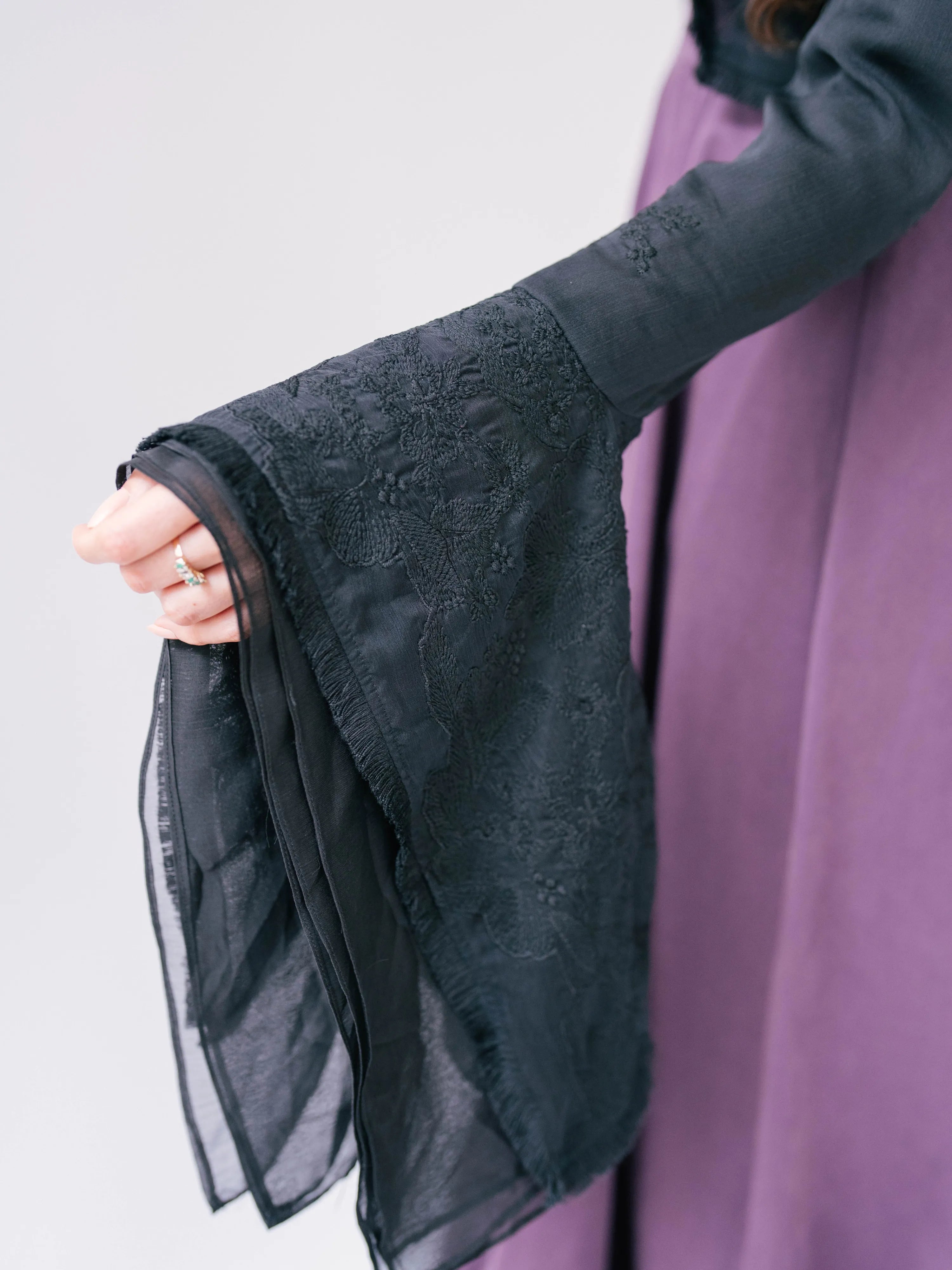 Black lace-trimmed sleeve with delicate floral embroidery.