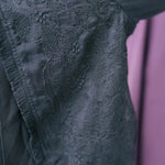 Zoomed in shot of the bolero jackets bell sleeves. Showing black lace fabric with delicate floral embroidered patterns.