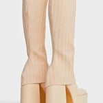 Cream-colored platform boots with chunky heels and ribbed fabric texture.