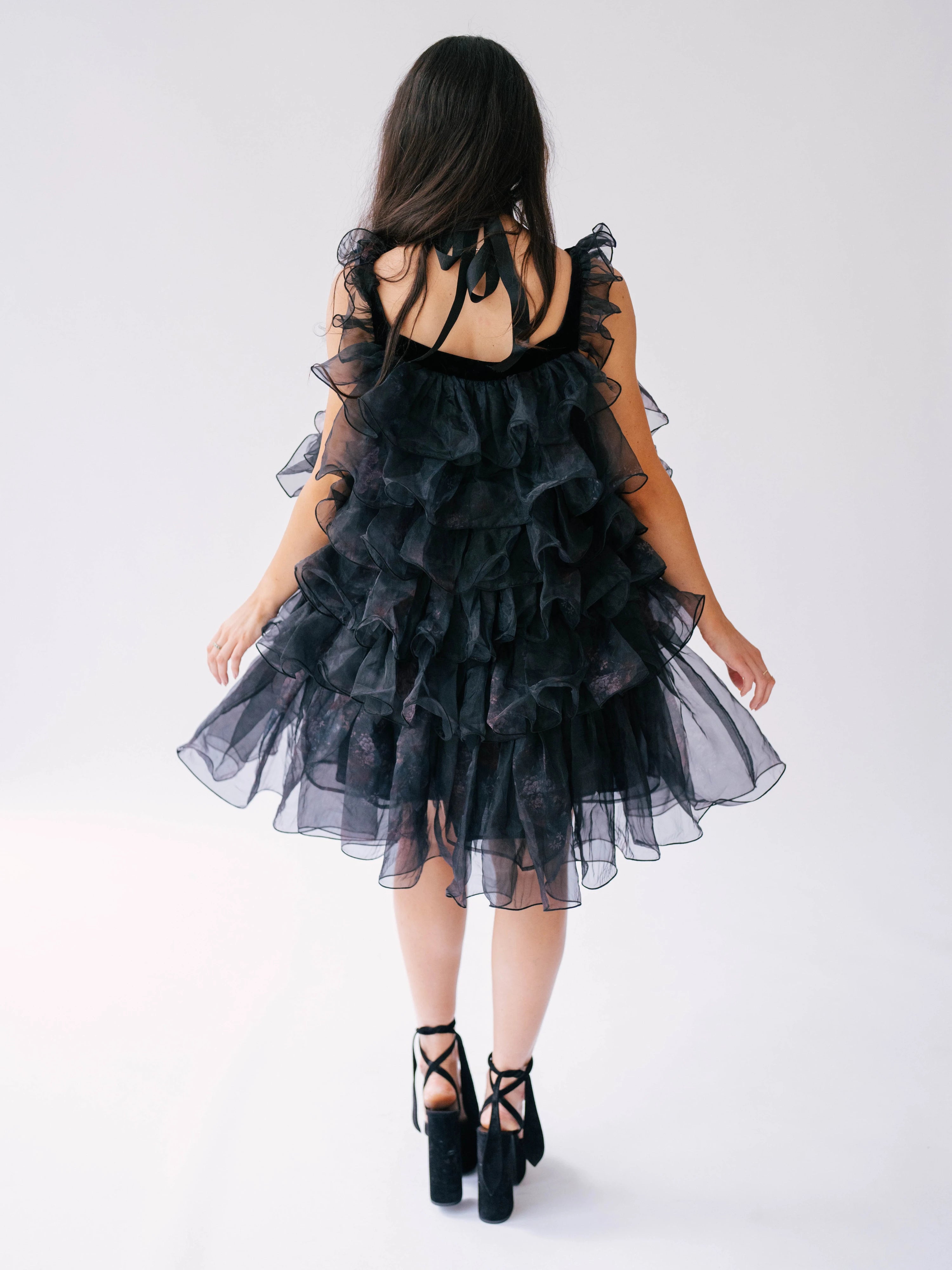 Black ruffled organza poofy dress with tiered layers, paired with black platform heels.