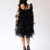 Black ruffled poly organza poofy cocktail dress with straps and tiered organza layers.