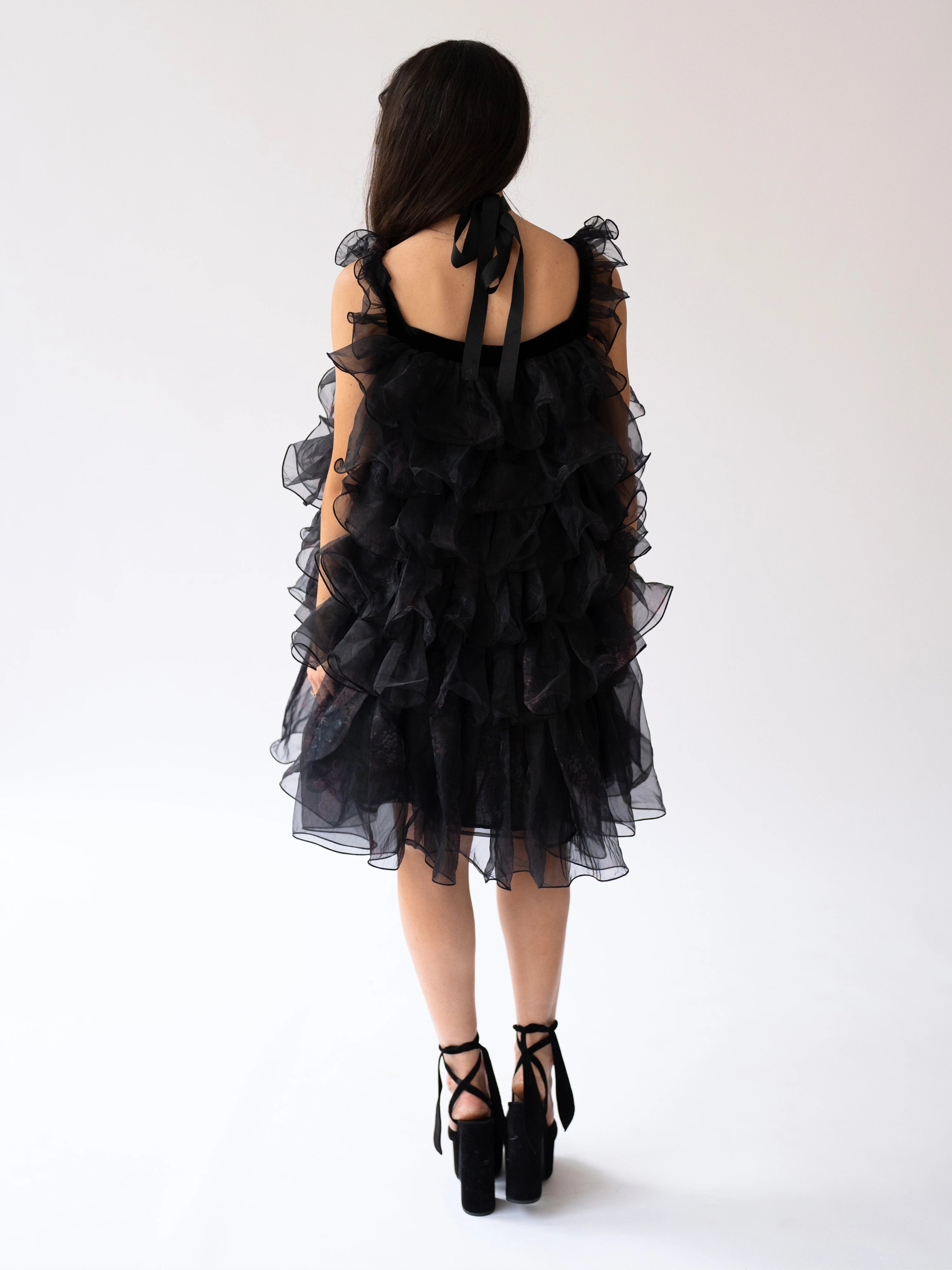 Black ruffled poly organza poofy cocktail dress with straps and tiered organza layers.