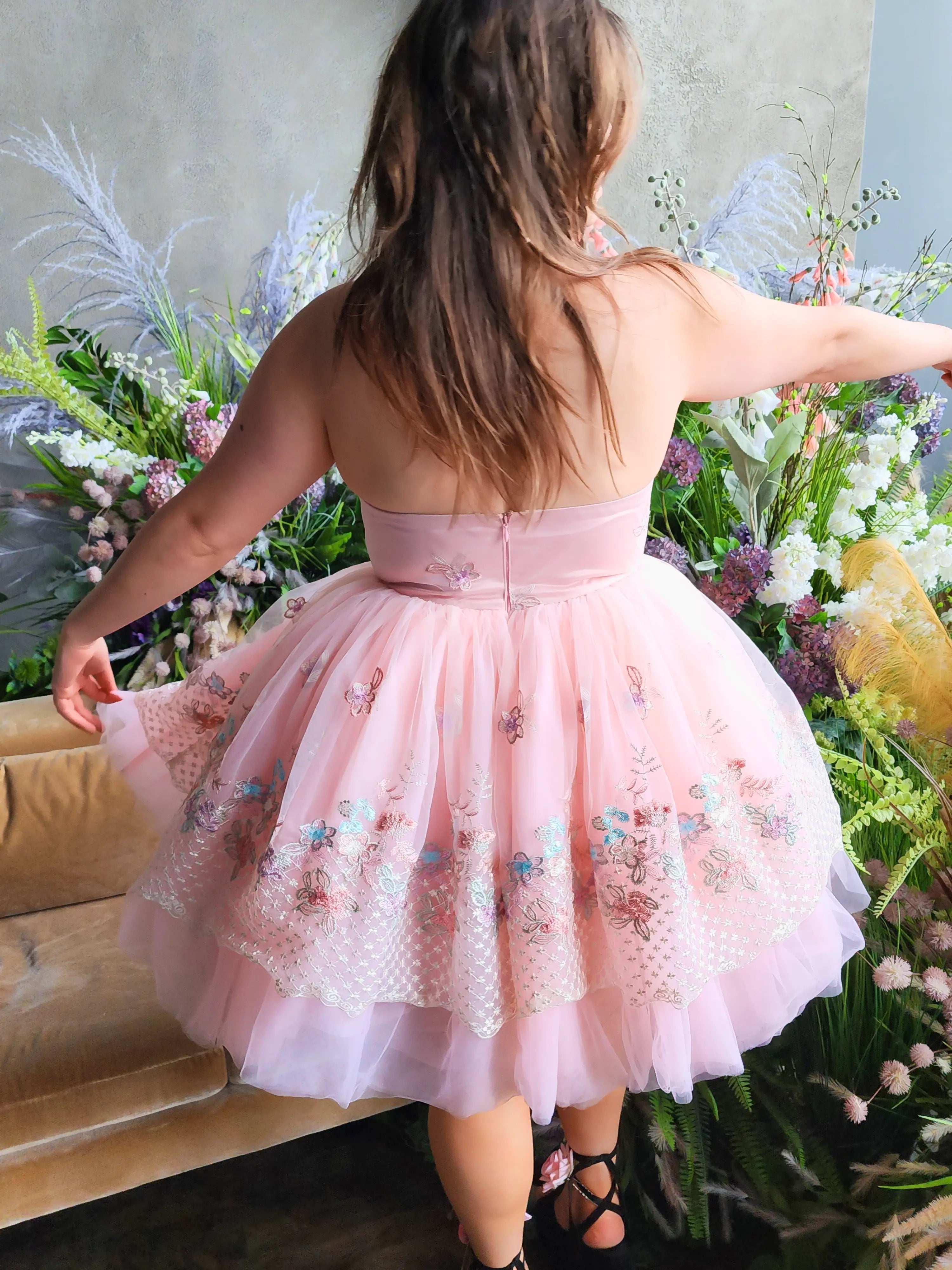 Pink tulle party dress with floral embroidery, shown on model from the back.