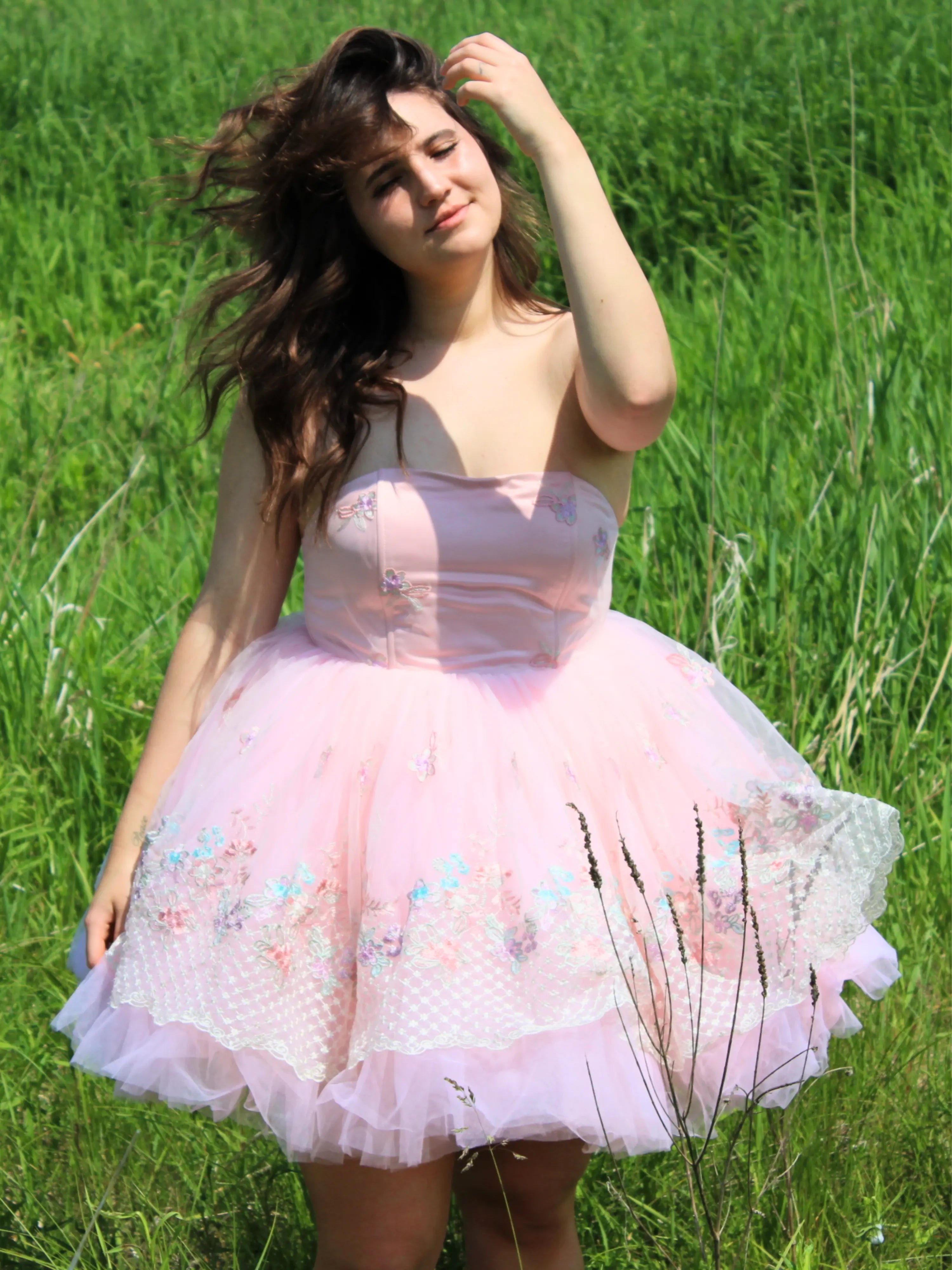 Pink tulle Magnolia Fairy Tutu Dress with lace details worn by a model in a tall grass field for a whimsical effect.